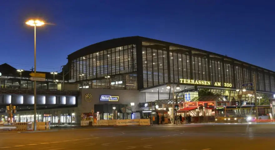 Der Bahnhof Zoo in Berlin bei Nacht. Die beleuchteten Terrassen am Zoo erstrahlen im Dunkeln.