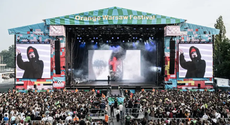 Tłum ludzi na Orange Warsaw Festival 2026, scena z artystą na ekranie i dymem.