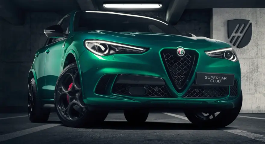 Zielony Alfa Romeo Stelvio Quadrifoglio z czarnymi felgami i czerwonymi zaciskami hamulcowymi, zaparkowany w garażu.