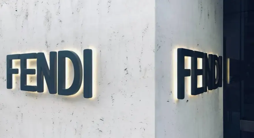 Insegna luminosa Fendi su una parete di marmo. Il **Fendi significato** è lusso e artigianalità italiana.