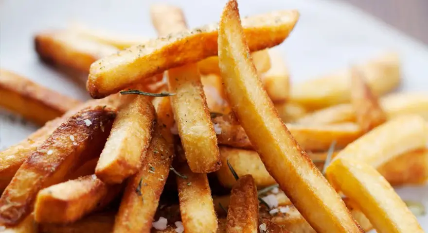 En hög med gyllene, krispiga pommes frites, strödda med örter och havssalt. Perfekt för en mysig hemmakväll.