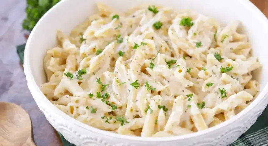Penne w kremowym sosie śmietanowym, posypane świeżą natką pietruszki. Idealne na szybki obiad.