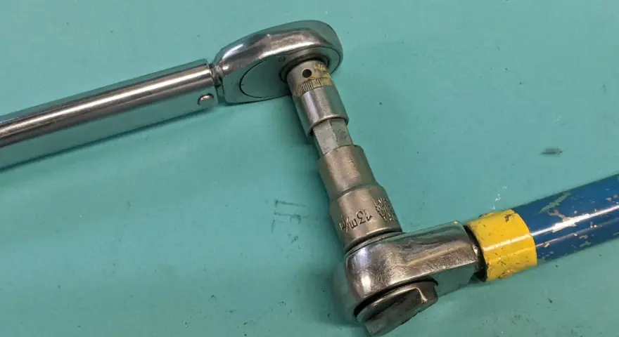 Två verktyg kopplade för att kalibrera momentnyckel. En momentnyckel i metall och en blå/gul skruvdragare med hylsa.