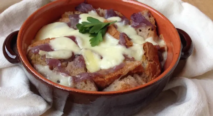 Zuppa di cipolle toscana fumante, con crostini dorati e formaggio filante, guarnita con prezzemolo fresco.