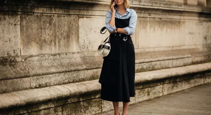 Mujer con un elegante vestido negro sobre una camisa blanca, hablando por teléfono.