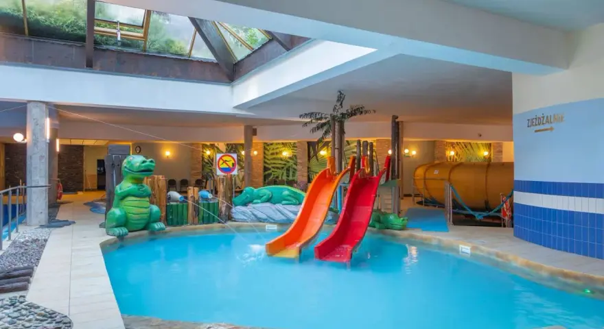 Karpacz hotel z basenem i atrakcjami dla dzieci: zjeżdżalnie, basen, zielone dinozaury i tropikalne dekoracje.