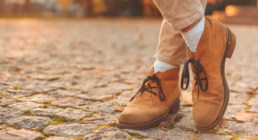 Herbstliche Stiefeletten aus Nubukleder, was das ist, zeigen sich auf einem Kopfsteinpflaster.