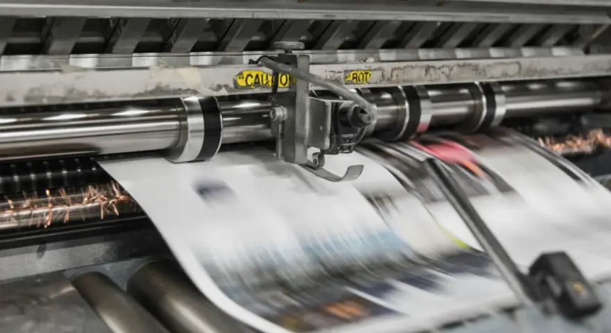 Maszyna drukarska w ruchu, tworząca strony gazet metodą wklęsłą lub offsetową.