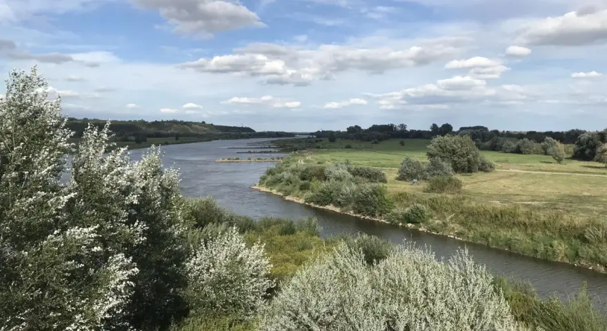 Malowniczy krajobraz z rzeką i zielonymi wzgórzami, idealny na sandomierz trasy rowerowe.