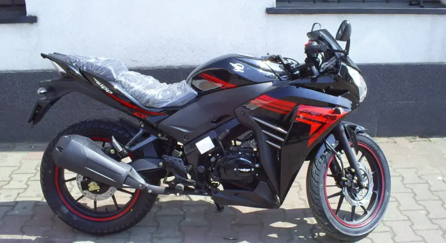 Czarny motocykl Zipp Xrace 50 z czerwonymi akcentami, gotowy do jazdy po miejskich ulicach.