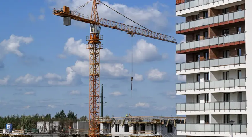 Plac budowy, gdzie lex deweloper wznosi nowoczesne apartamenty. Widoczny dźwig budowlany i postępujące prace.