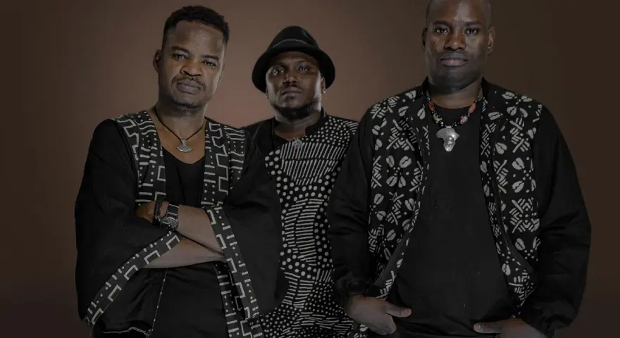 Trois hommes en tenue traditionnelle africaine, évoquant l'ancêtre du blues, posent avec assurance.