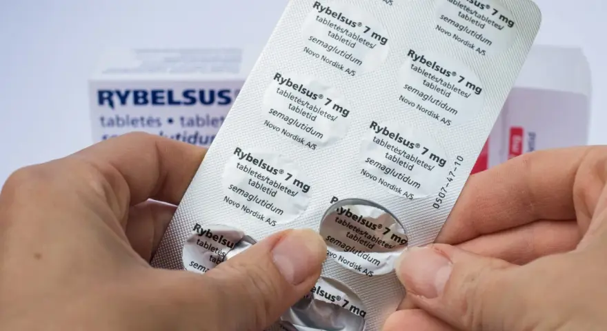 Dłonie trzymają opakowanie leku Rybelsus 7 mg. Cena Rybelsus jest ważnym czynnikiem dla pacjentów.