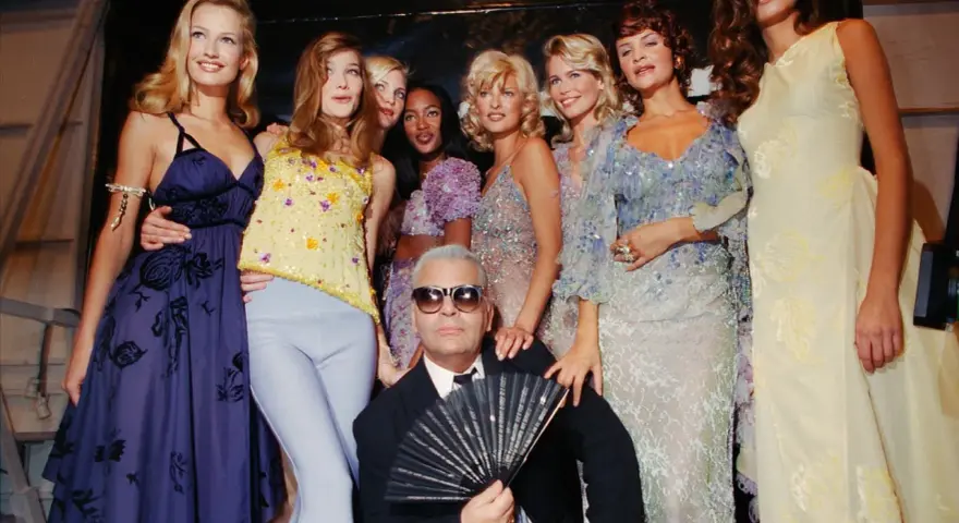 Karl Lagerfeld et des mannequins posent pour une soirée année 90 comment s'habiller. Tenues scintillantes et robes fluides.