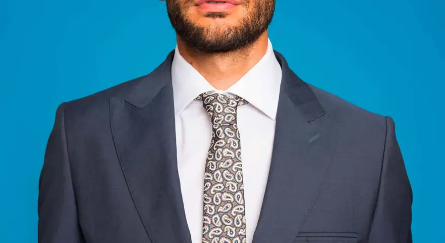 Uomo con abito blu, camicia bianca e cravatta fantasia. Un abbinamento classico per un look elegante.
