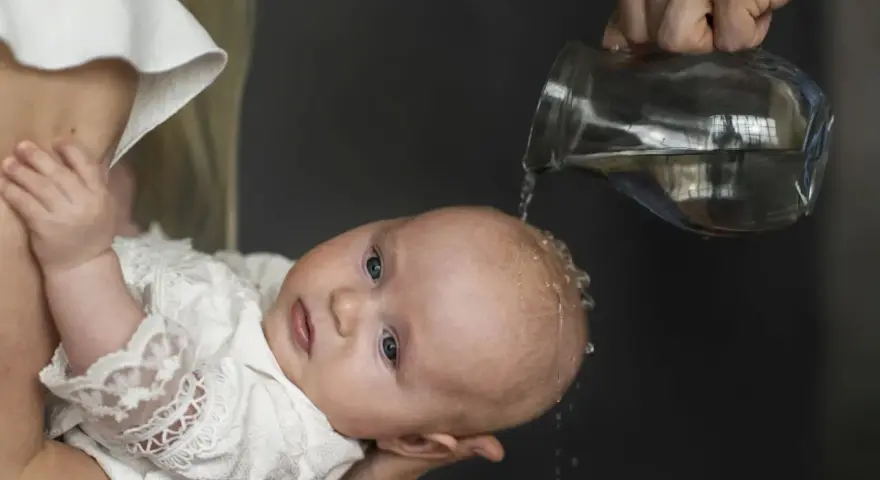 Chrzest chłopca: polewanie główki wodą z dzbanka.