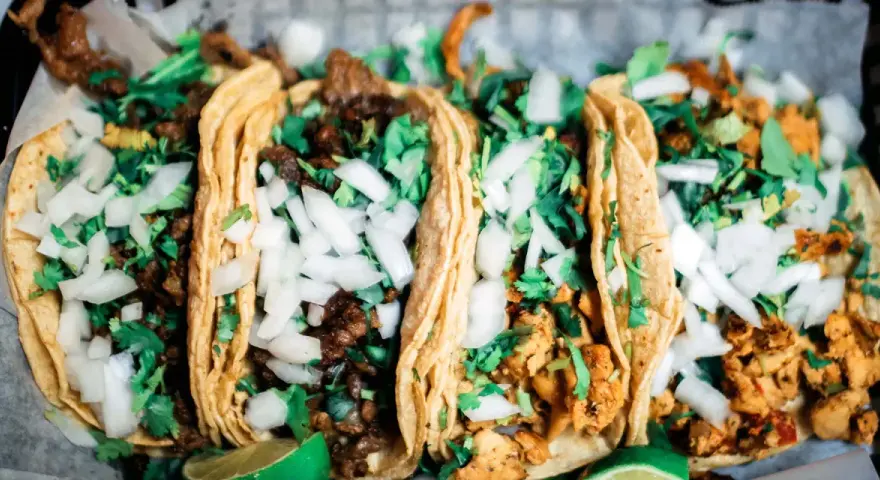 Fünf köstliche Tacos mit Rindfleisch und Hähnchen, garniert mit Zwiebeln und Koriander. Perfekt für einen Taco-Abend!