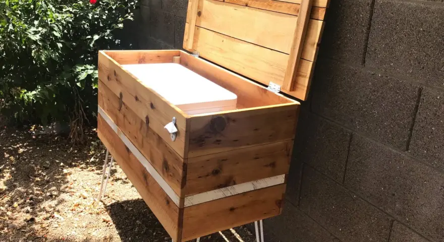 Wooden DIY deck box with lid open, showing white interior, on hairpin legs.