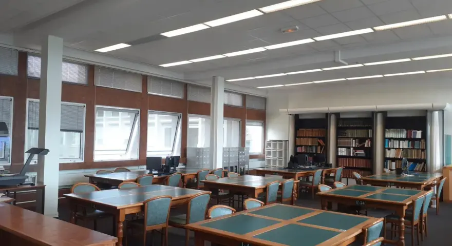 Salle de lecture avec tables, chaises et étagères de livres.
