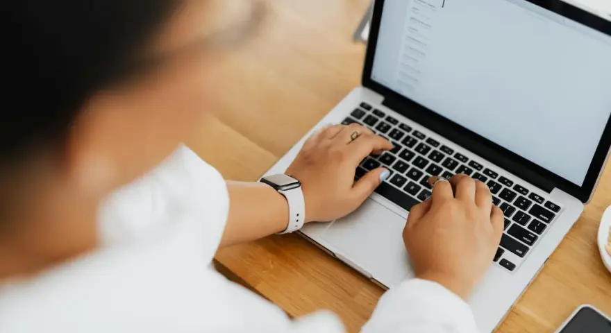 Kobieta pisze na laptopie, na ekranie widać artykuł po niemiecku.