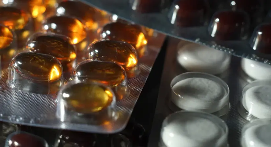 Närbild på flera blisterförpackningar med piller. En förpackning innehåller gulaktiga kapslar, en annan vita tabletter och en tredje mörkbruna piller. Kanske en av dem innehåller folic acid svenska.