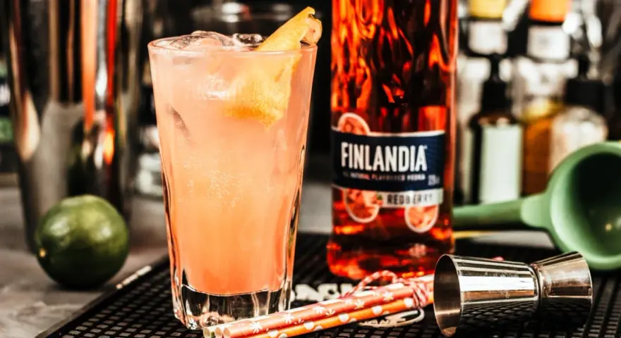 Orzeźwiające drinki z Finlandia Redberry, idealne na letnie wieczory. W szklance różowy koktajl z lodem i skórką cytrusową.