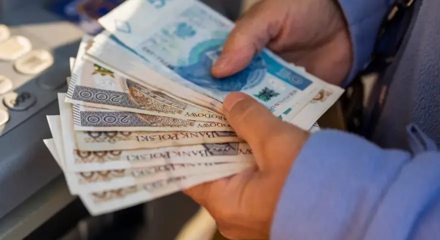 Ręce trzymające stos banknotów 200 zł i 50 zł. Zastanawiasz się, renta alkoholowa ile wynosi?