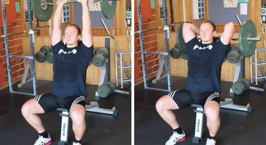 Man utför french press i gym. Han sitter på en bänk med en skivstång över huvudet, redo att sänka den bakom nacken.