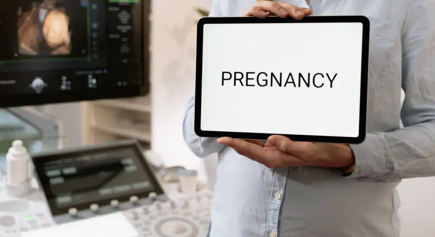 Wczesna ciąża, 2 tydzień. USG pokazuje zarodek, a na tablecie widnieje napis "PREGNANCY".