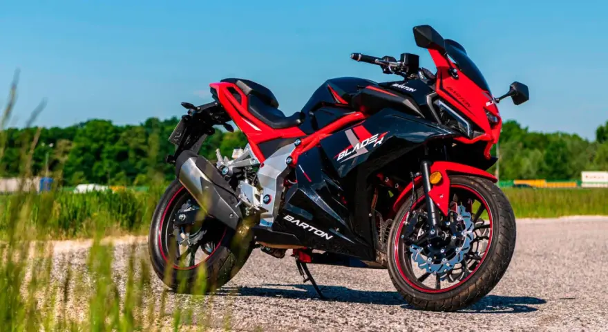 Czarny sportowy motocykl Barton Blade R 125 V Max z czerwonymi akcentami, zaparkowany na drodze w słoneczny dzień.