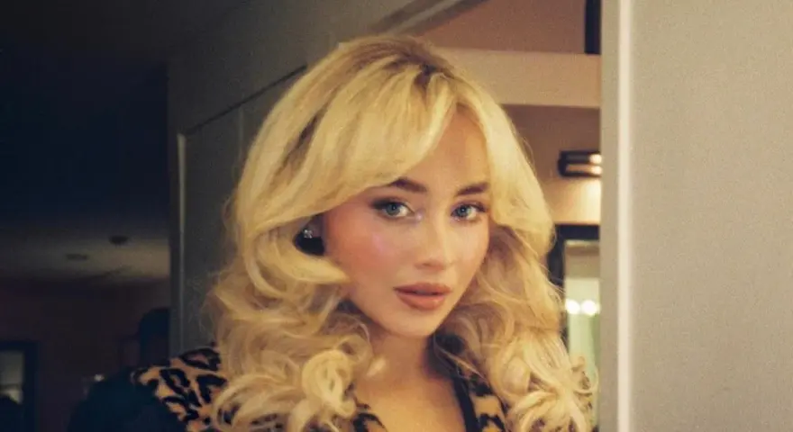 Frau mit voluminösem blondem Haar und Leopardenmuster-Jacke.