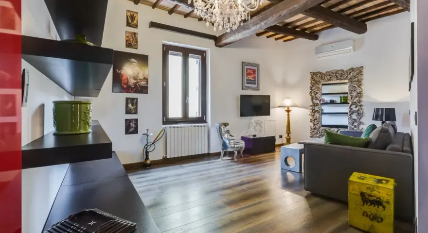 Soggiorno con travi a vista, lampadario di cristallo e un tocco di stile rustico.