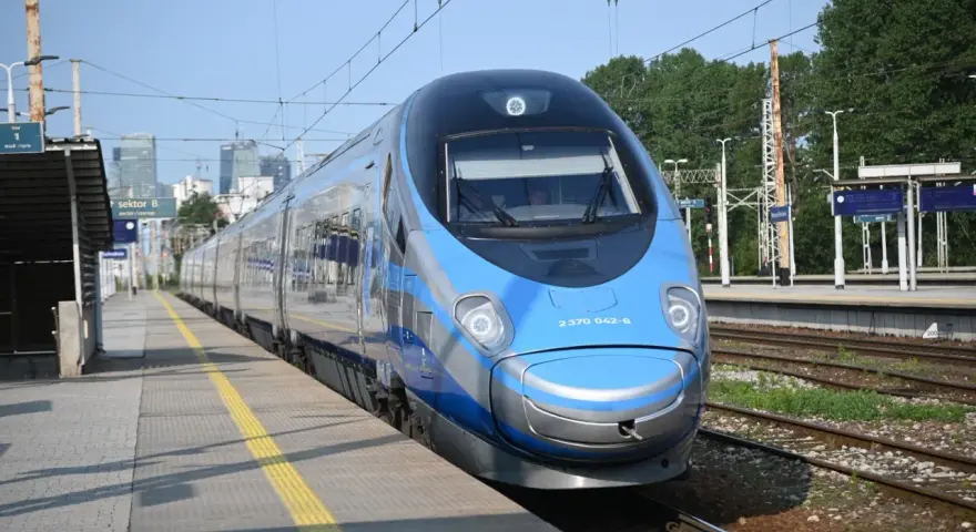 Niebiesko-srebrny pociąg Pendolino na peronie dworca kolejowego.
