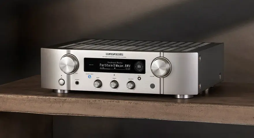 Srebrny wzmacniacz Marantz PM7000N, gotowy do testu, z wyświetlaczem pokazującym utwór muzyczny.