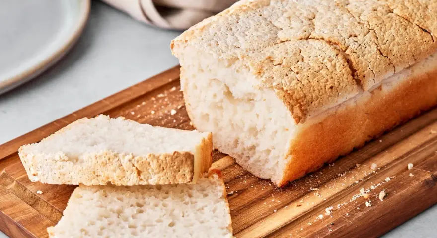 Ein Laib japanisches Reisbrot, aufgeschnitten auf einem Holzbrett. Dieses Rezept für japanisches Reisbrot ist perfekt für alle, die glutenfreies Brot lieben.