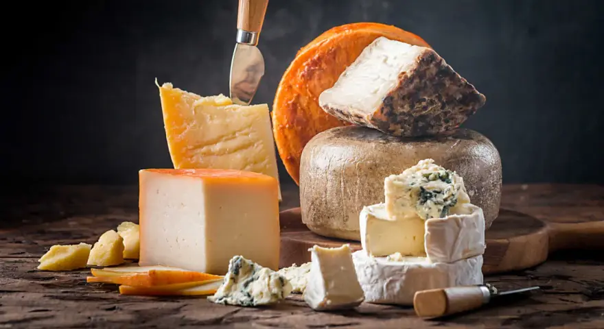 Kuski najlepsze sery: parmezan, pleśniowy, camembert i inne, ułożone na drewnianej desce.