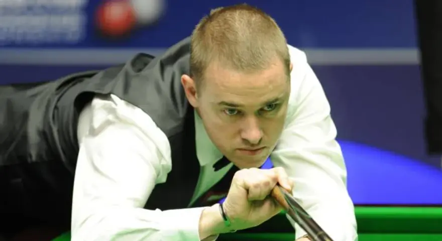 Gracz snookera w skupieniu celuje kijem do bili. Czy to on zostanie mistrzem świata w snookerze 2025?