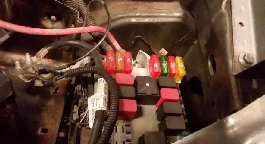 Skrzynka z bezpiecznikami w Fiat Doblo. Widać kolorowe bezpieczniki i przekaźniki.