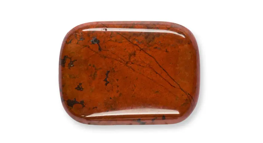 Una piedra de jaspe rojo pulido, con vetas oscuras y manchas, que muestra la belleza natural de que es el jaspe.