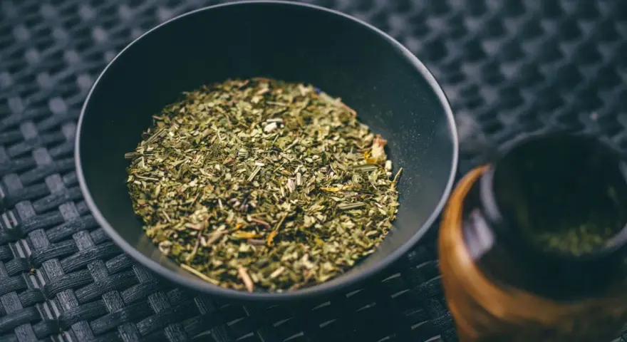 Suszone liście yerba mate w czarnej miseczce, gotowe do zaparzenia. To naturalny napój pobudzający.