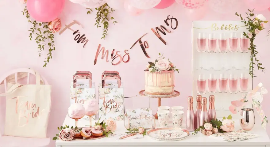 Uroczy wystrój na wieczór panieński: tort, balony, napisy "From Miss To Mrs", torby "Team Bride" i kieliszki z różowym napojem. Idealne pomysły, co robic na panieńskim!