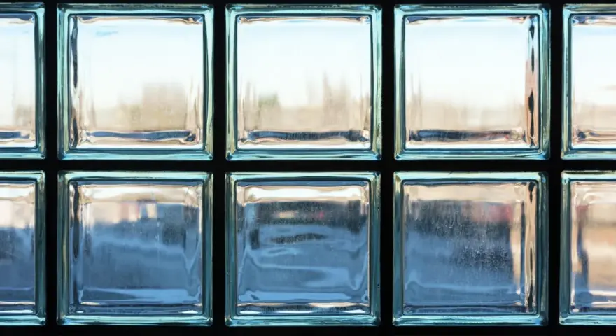 Un mur en brique de verre, reflétant la lumière extérieure, crée une ambiance douce et diffuse.