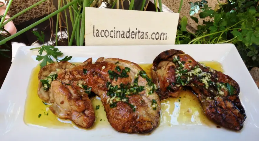 Delicioso hígado de rape a la plancha con ajo y perejil, servido en una bandeja blanca.