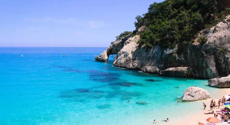Cala Goloritze: turkusowa woda, skaliste klify i plażowicze cieszący się słońcem.
