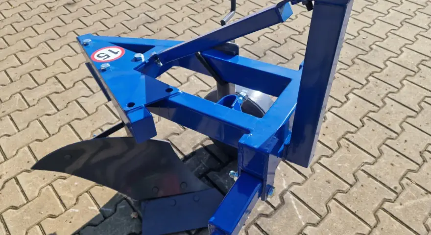 Niebieski pług 1 skibowy gotowy do pracy na polu. Solidna konstrukcja i ostry lemiesz zapewnią efektywne przekopywanie ziemi.