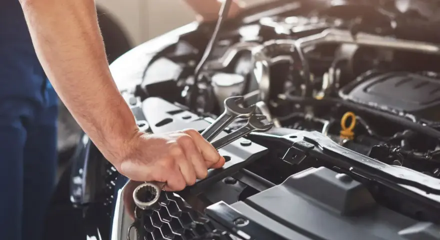 Mechanik sprawdza objawy awarii pompy paliwa Audi A4 B6 1.8T. W dłoni trzyma klucze.