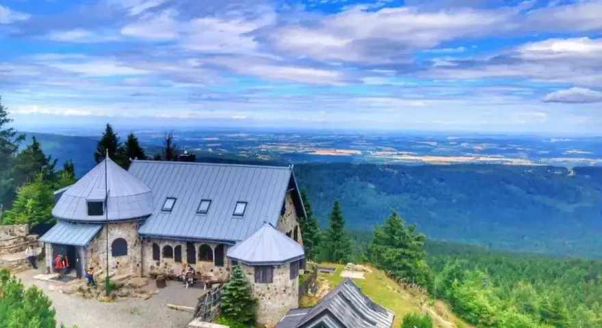 Kamienny schron turystyczny na tle rozległej panoramy Gór Izerskich. Wspaniałe widoki z górskich szlaków.