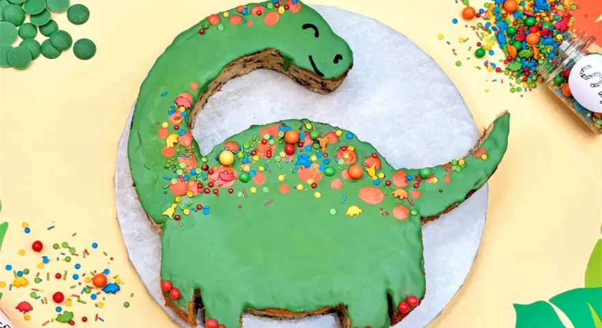 Grüne Dinosaurier Torte selber machen: Ein süßer Dino mit bunten Streuseln und Schokodrops. Perfekt für kleine Entdecker!