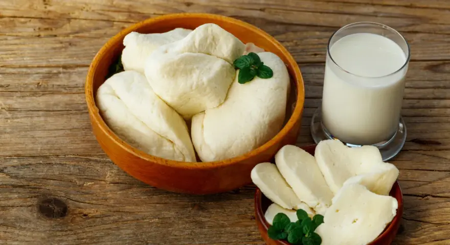 Ser halloumi w ciąży: świeży ser i szklanka mleka na drewnianym stole. Idealne dla przyszłej mamy.