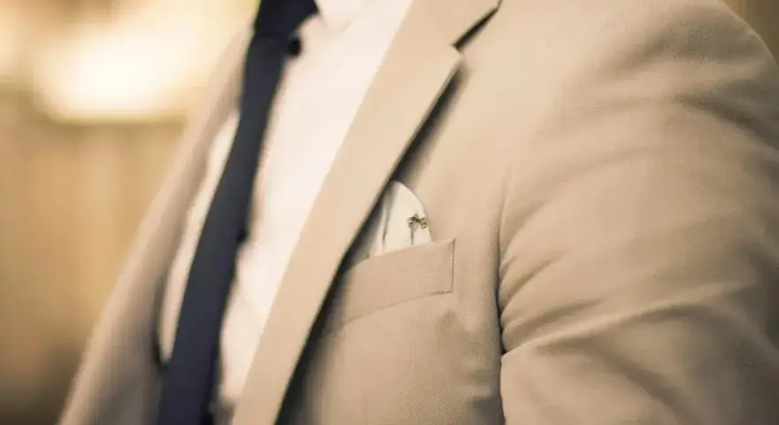 Elegancki mężczyzna w jasnej marynarce i granatowym krawacie. Zastanawiasz się, ile zarabia manager hotelu?